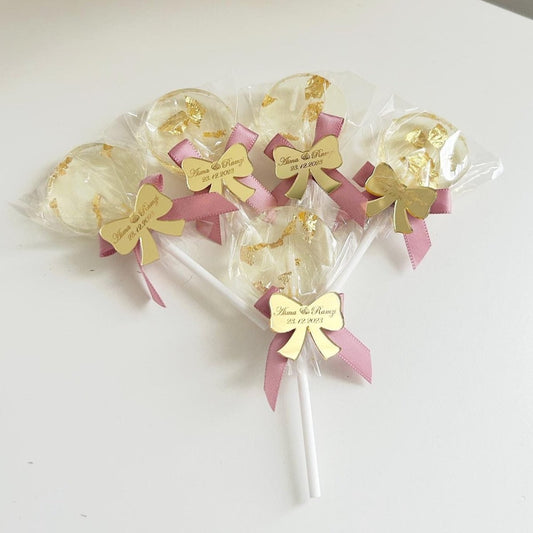 Sucette Minnie Rose avec feuille d’or comestible et étiquette en plexiglas doré en forme de nœud