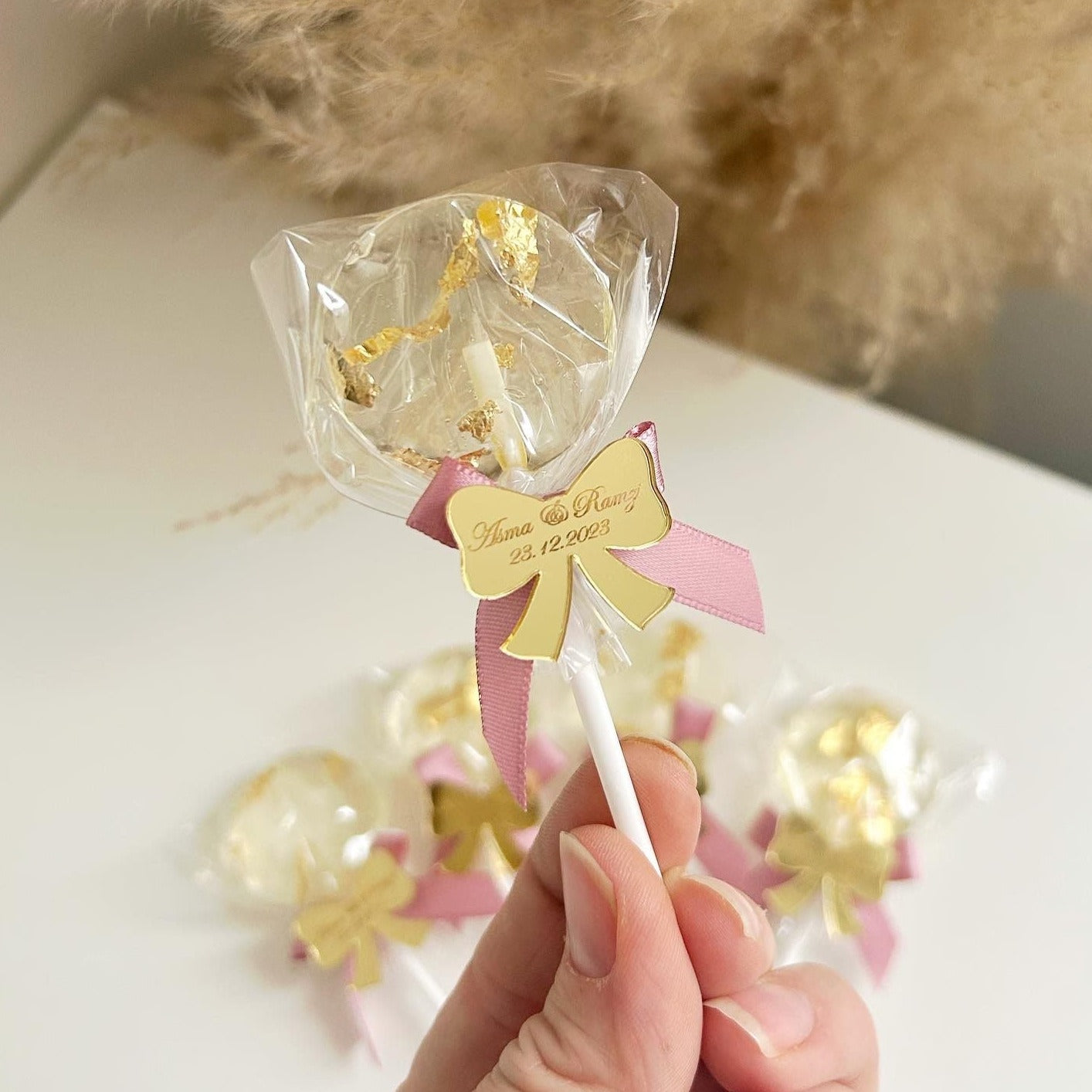 Sucette Minnie Rose avec feuille d’or comestible et étiquette en plexiglas doré en forme de nœud