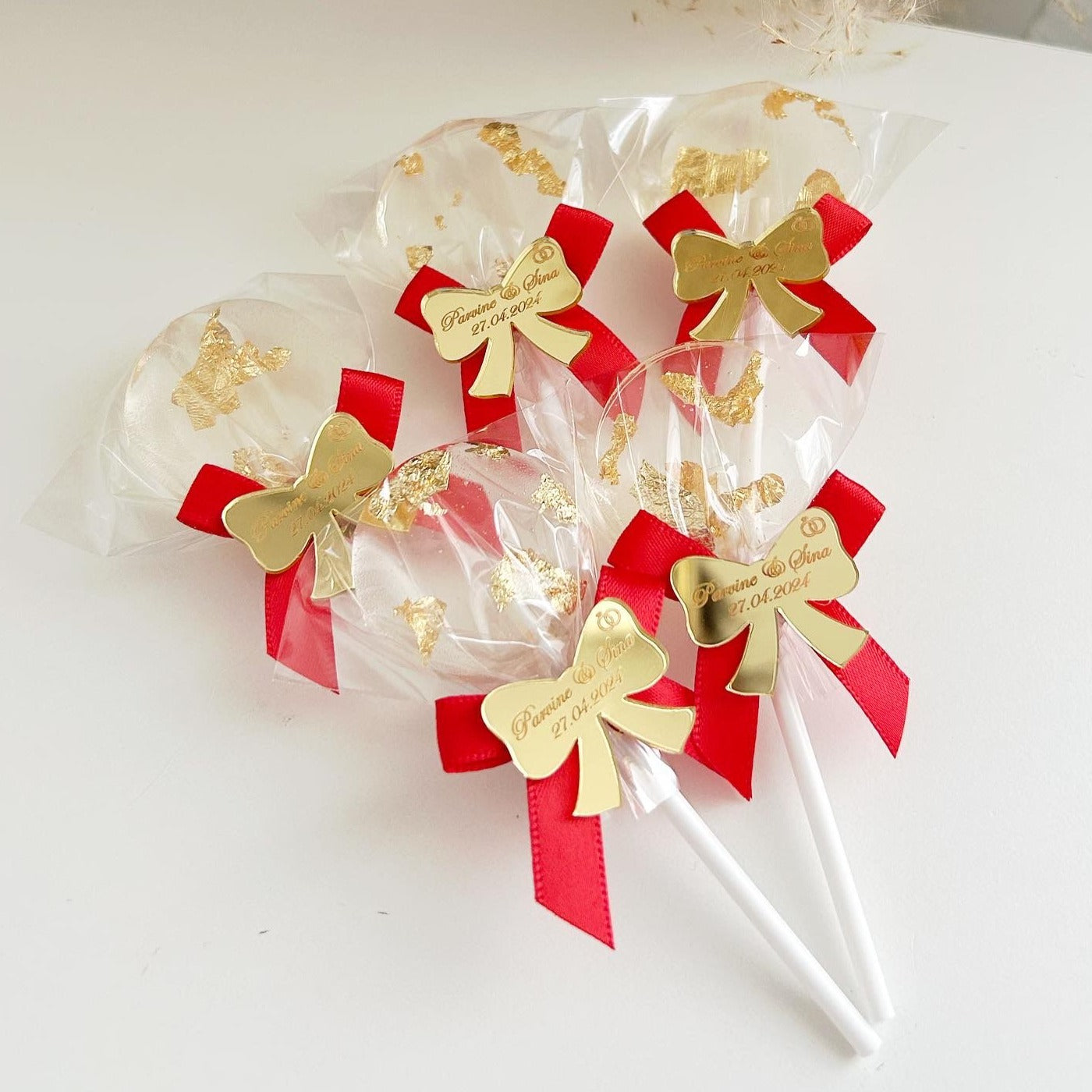 Sucette Minnie Rouge avec feuille d’or comestible et étiquette en plexiglas doré en forme de nœud